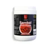 Sambal Chilli Paste in a jar with a spoonful of spicy paste next to a plate of fried rice and fresh vegetables
